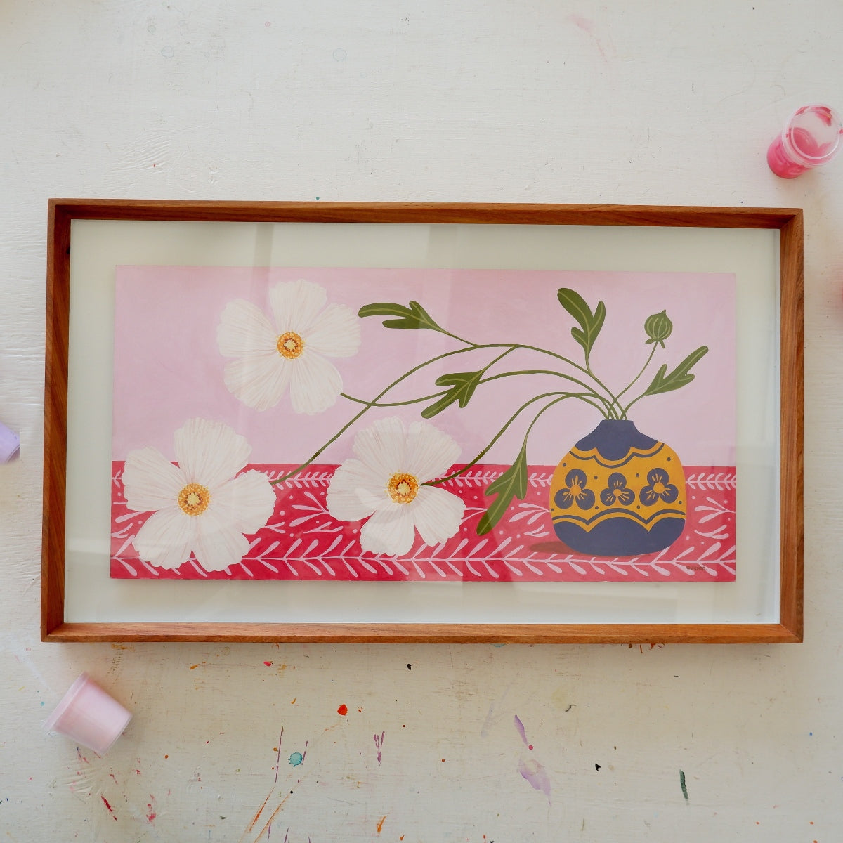 Framed artwork with white flowers and a vase on a pink background